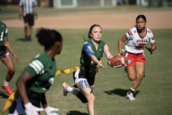 Sophomore quarterback Abby W. pitches the football as Layla R. '27 looks back. The Tigers played Ayala in the season opener, losing 19-6, but went on to win four straight games after that.